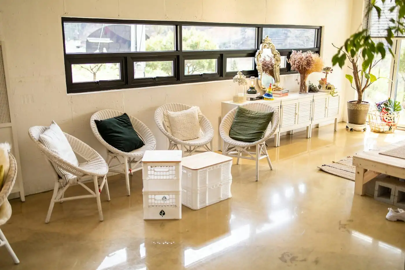 The bright, oat-coloured reception lobby with a bench, plants and a wall of framed guest photos